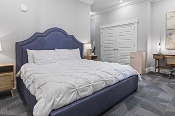 A bedroom with a bed and a dresser and a closet